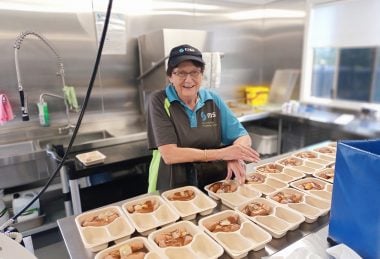 A My Meals volunteer packs food in a kitchen, showing the community spirit that deserves to be celerbated through volunteer recognition.
